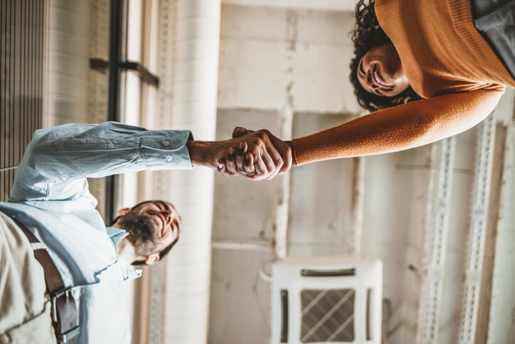 Man and woman shaking hands in an office interior, viewed from below