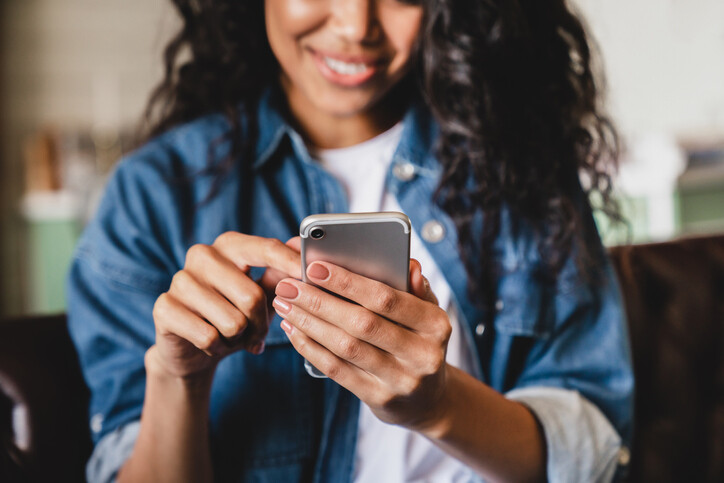 Smiling woman using a smartphone at home for lead nurturing and customer follow-up